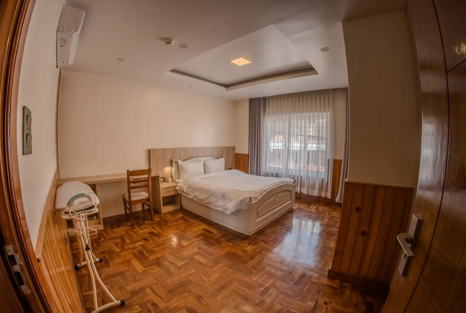 Simple bedroom with painted wooden bed and desk